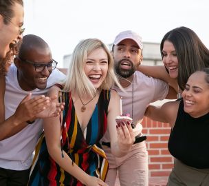 Excited young diverse friends celebrating birthday of cheerful woman on terrace
